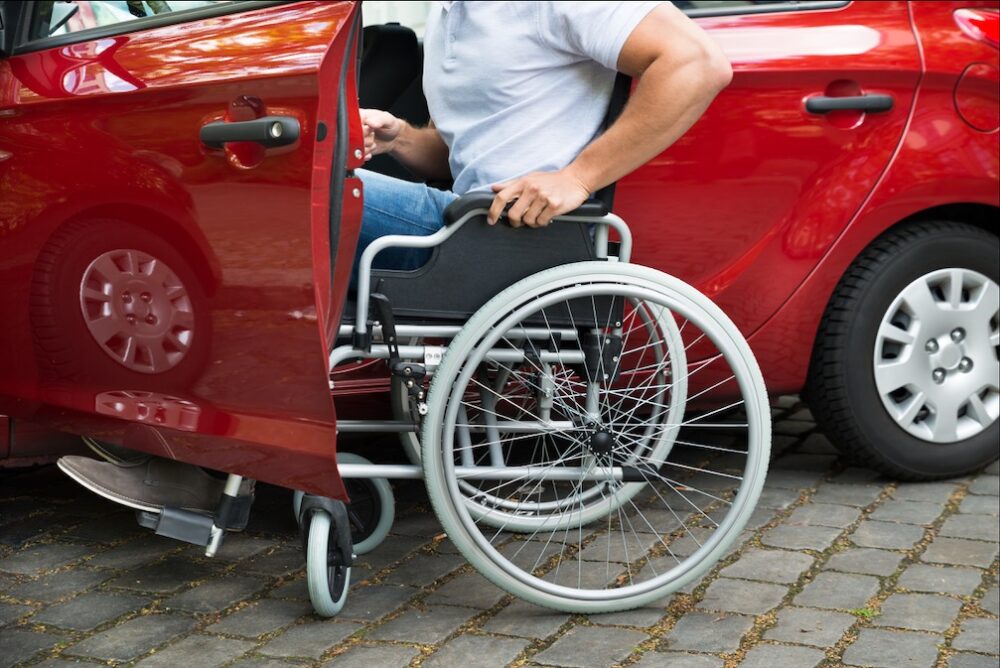 Homem em cadeira de rodas entrando em seu carro