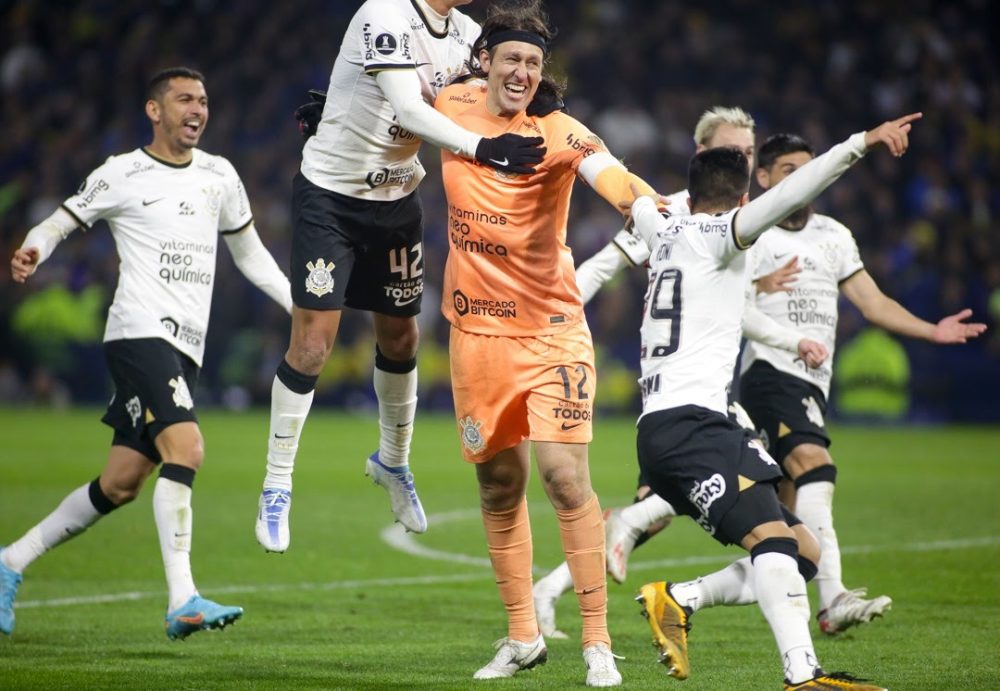 Cássio ao centro da imagem, com uniforme laranja, cercado por outros jogadores do Corinthians que celebram a classificação às quartas de final - roteiro a la Corinthians